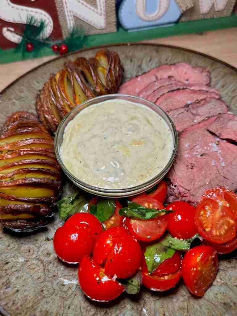 Steak, hassleback potatoes, cherry tomatoes, and a dip